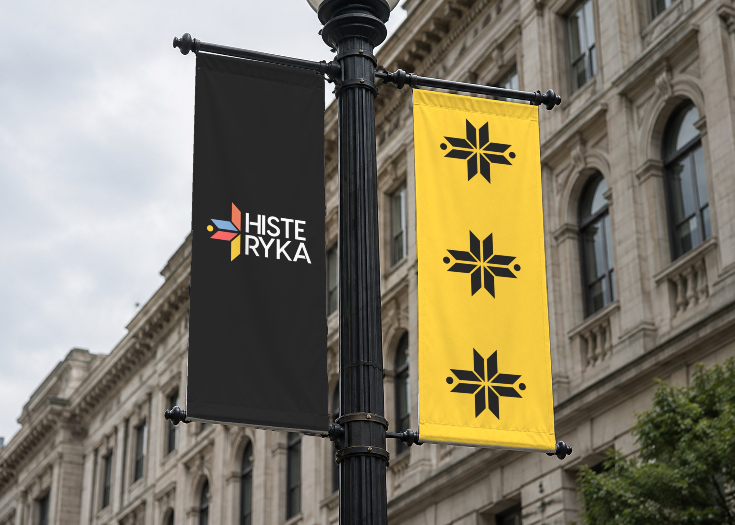 HISTERYKA banners on a street lamp: the logo on black and the ornament stars on yellow