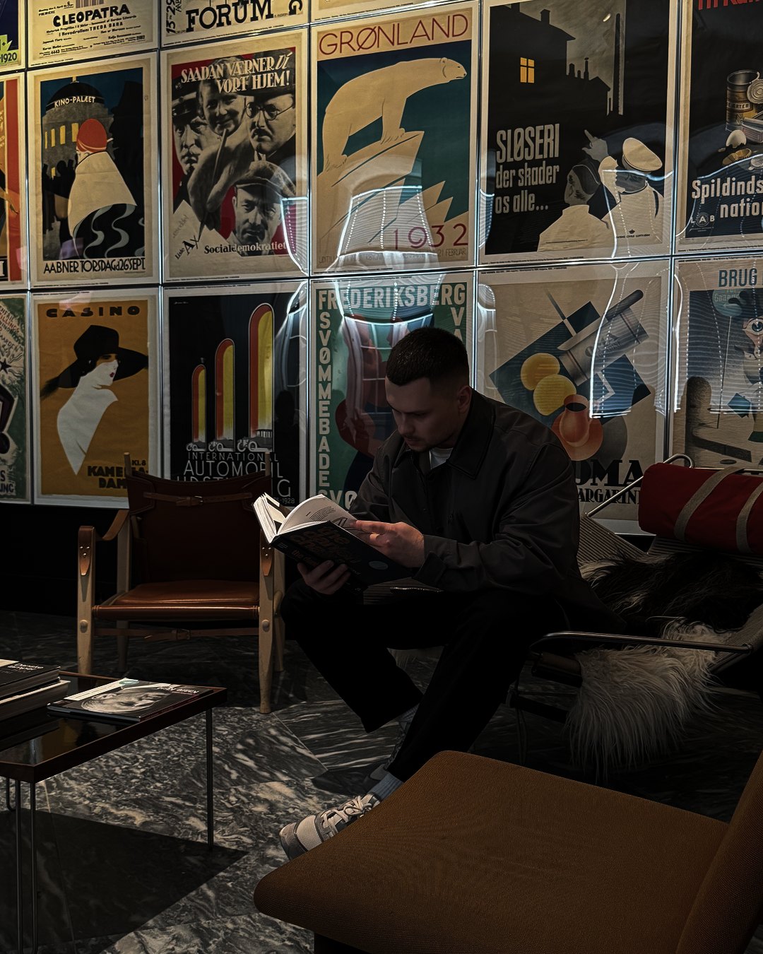 Vlad Mosin reading a book in front of a wall of vintage posters